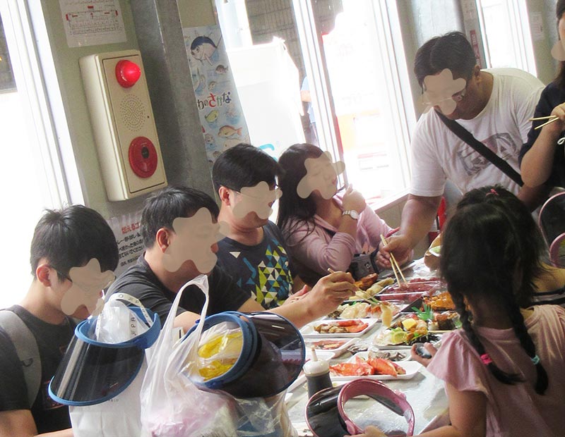 沖縄県糸満市　道の駅いとまん　外国人の家族がお刺身やエビを食べている風景