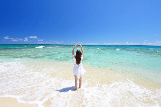 福岡発　GW　沖縄　格安ツアー　青い海で背伸びしている女性